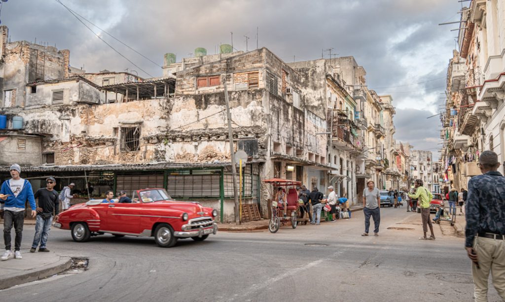 A red classic car on a weathered Havana street
Sixty Years of Communism by Mary Peddecord